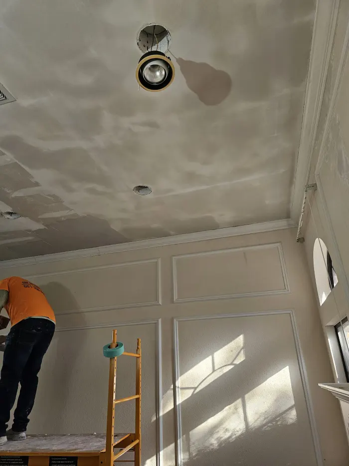 Ceiling drywall being sanded after finish work